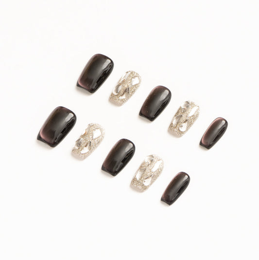 Flat lay of ten press-on nails arranged in two rows on a white background, featuring a dark plum and silver color palette. The set includes glossy deep purple cat-eye nails with subtle magnetic shimmer, paired with high-shine silver glitter accent nails adorned with sculptural metallic chain-style embellishments for a bold, modern luxe look.