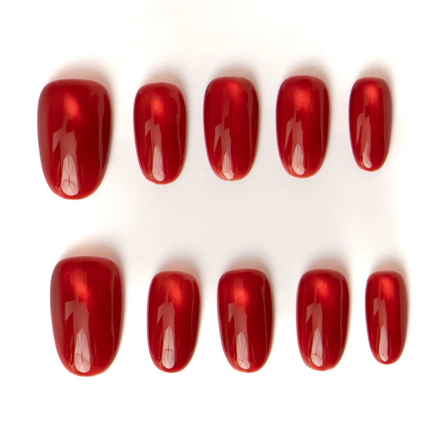 Close up of red cat eye press-on nails showing glossy top coat and almond shape.