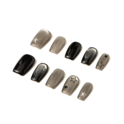 Side view of black and silver press-on nails showing glossy finish and hand-painted star details.