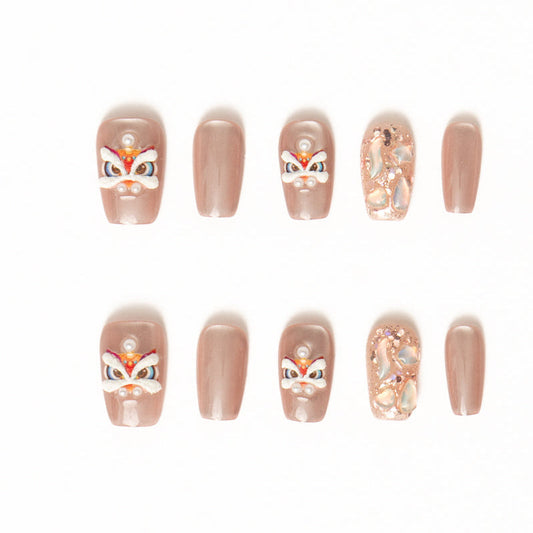 Flat lay of ten press-on nails arranged in two rows on a white background, featuring a soft nude-beige palette. The set includes glossy solid nude nails, accent nails with delicate pearl details, abstract iridescent shell textures, and playful hand-painted mask-inspired designs with white, red, and gold accents for an elegant yet whimsical look. Lunar New year nails