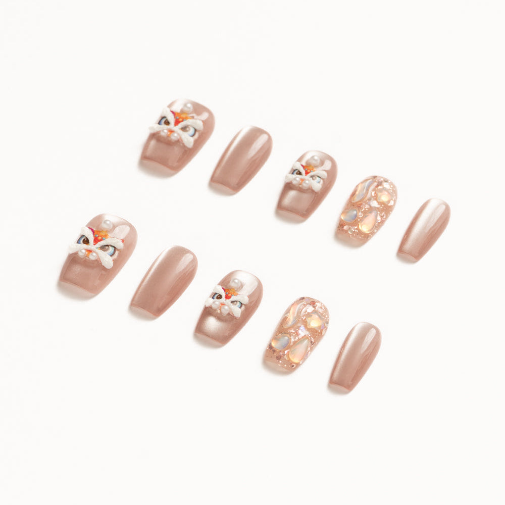 Flat lay of ten press-on nails arranged in two rows on a white background, featuring a soft nude-beige palette. The set includes glossy solid nude nails, accent nails with delicate pearl details, abstract iridescent shell textures, and playful hand-painted mask-inspired designs with white, red, and gold accents for an elegant yet whimsical look. Lunar New year nails