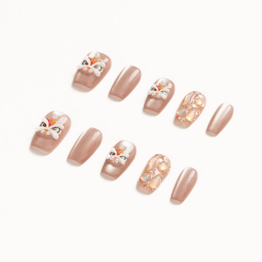 Flat lay of ten press-on nails arranged in two rows on a white background, featuring a soft nude-beige palette. The set includes glossy solid nude nails, accent nails with delicate pearl details, abstract iridescent shell textures, and playful hand-painted mask-inspired designs with white, red, and gold accents for an elegant yet whimsical look. Lunar New year nails