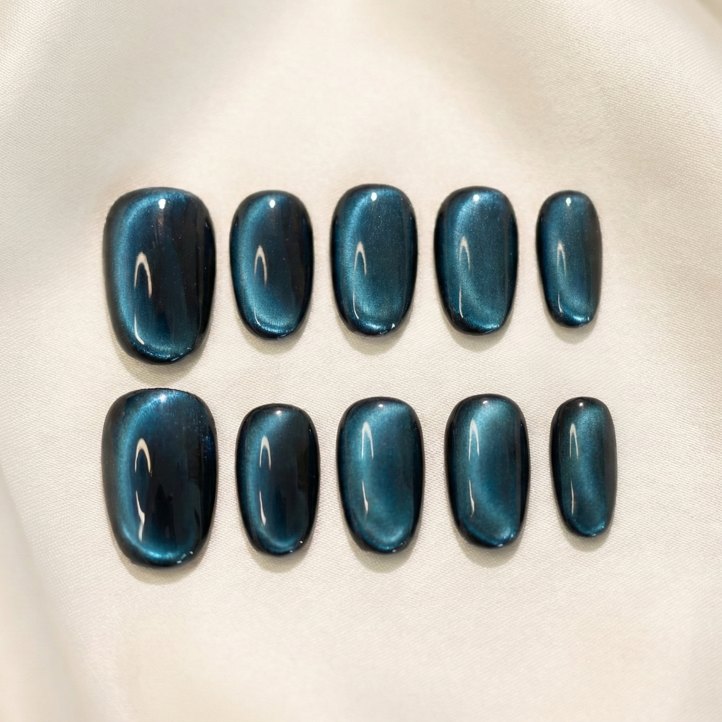 oval shape high quality Full set of dark petrol blue velvet cat eye press-on nails, showing the magnetic shimmer and glossy top coat.